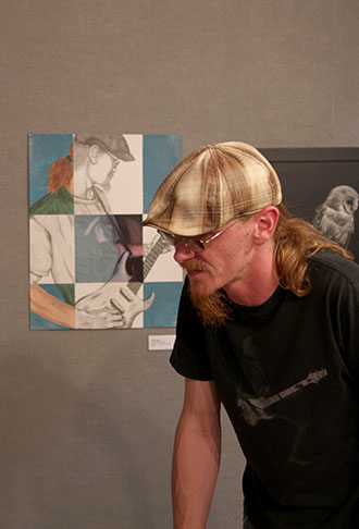 Jared Hegg admires other art as his own piece hangs in the background.